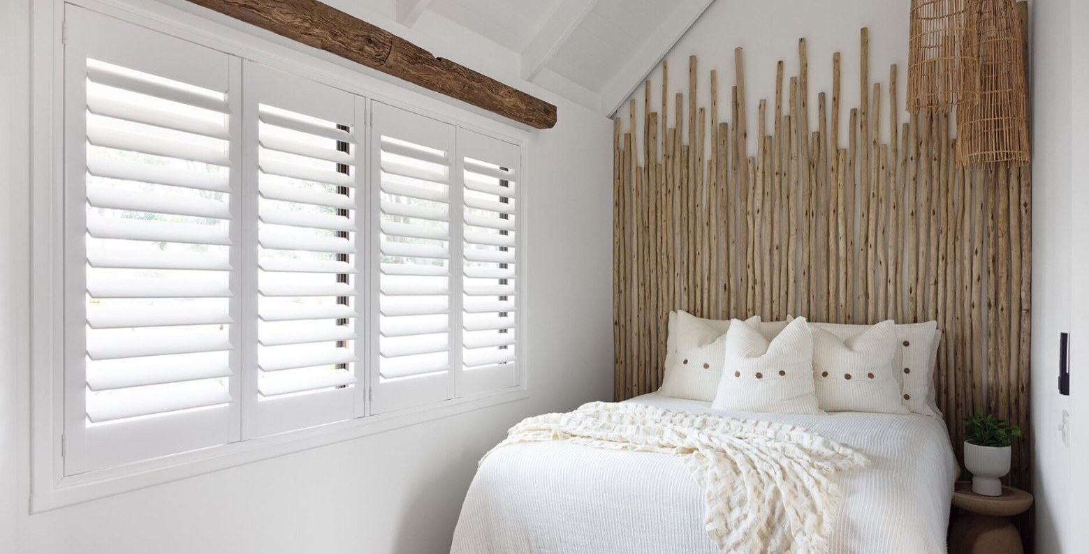 White plantation shutters filtering daylight in a bright bedroom