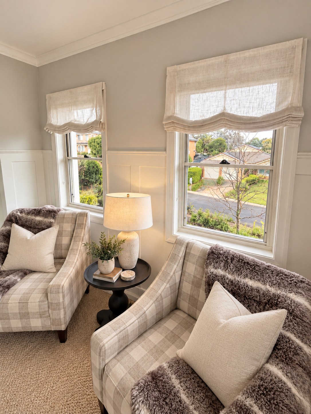 Soft-fold Roman blinds in a neutral living room with checkered armchairs