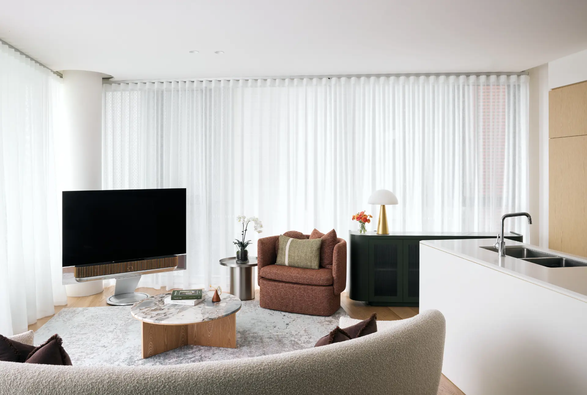 Full-height sheer curtains wrapping a bright open-plan living room